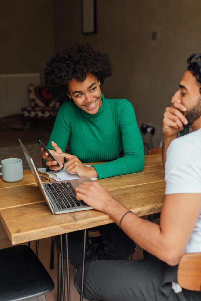 pexels-photo-5332279-5332279 Two adults collaborating at a wooden table with laptops and phones in a cozy indoor setting.